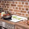 A kitchen counter with a glass stovetop protector featuring a cactus design, a frying pan, and various ingredients. Voir les images du produit