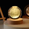 A crystal sphere with a 3D moon inside, illuminated from within, resting on a wooden base. Anteprima dell’immagine prodotto