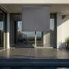 An outdoor patio with a gray roller blind extended over a glass door. Náhled obrázku produktu