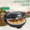 A pizza oven is shown with a pizza inside, set against a backdrop of Italian-style buildings and rolling hills. Produktbild-Vorschau