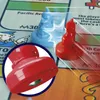 Close-up of two Monopoly game tokens, one red and one blue, on a Monopoly board. Voir les images du produit