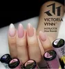 A hand with multiple nails painted in different shades of pink and nude gel polish, surrounded by several small jars of gel polish. Náhled obrázku produktu
