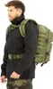 A man wearing a black jacket and camouflage pants is modeling a large olive green backpack. Náhľad obrázku produktu