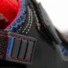 A close-up view of a black safety sandal, highlighting its stitching, red and blue accents, and a textured black detail. Produktbild-Vorschau