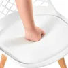 A hand is pressing into the cushion of a white chair. Náhled obrázku produktu