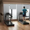 Two treadmills in a gym with a man running on one of them. Produktbild-Vorschau