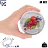 A hand holding a metal lid with a fruit design. Voir les images du produit