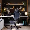 A gaming chair in a modern home office setup with a desk, computer, and decorative elements. Produktbild-Vorschau