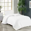 A white duvet and pillow set on a bed, with a large window and a plant in the background. Produktbild-Vorschau