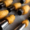 A close-up shot of several pastry cones on baking paper, each on a metal mold. Podgląd zdjęcia produktu