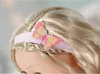 Close-up of a doll's head with blonde hair, wearing a pink headband with a butterfly decoration. Produktbild-Vorschau
