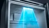 Interior view of a refrigerator with a blue light illuminating the shelves. Produktbild-Vorschau