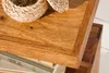 A close-up view of a wooden table surface with a woven basket and books. Produktbild-Vorschau