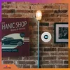 A smoke detector is mounted on a brick wall next to a vintage car poster and a floor lamp. Podgląd zdjęcia produktu