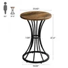 A round wooden table with a black metal base, shown with dimensions and a scale figure. Produktbild-Vorschau