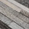 A close-up, angled view of a rug made of strips of cowhide. Voir les images du produit