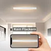 A hand holding a smartphone displaying a light fixture, with the actual light fixture visible on the ceiling above. Anteprima dell’immagine prodotto