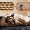 A Siamese cat is sleeping on a dark gray fluffy surface, with close-up images of sisal rope and particleboard panels above. Produktbild-Vorschau