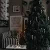 A Christmas tree decorated with candles and tinsel, placed next to a striped armchair and a table with decorative balls. Podgląd zdjęcia produktu