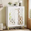 A white shoe cabinet with mirrored doors is shown in an entryway, with slippers placed underneath. Produktbild-Vorschau