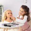 A young girl is applying makeup to a styling head. Náhled obrázku produktu