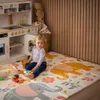 A toddler sits on a play mat next to a toy kitchen. Podgląd zdjęcia produktu