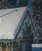 A log cabin decorated with icicle lights in a snowy forest setting. Voir les images du produit