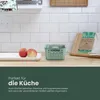 A kitchen counter with a green storage basket, apples, and a cutting board with beeswax wraps. Produktbild-Vorschau