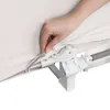 A close-up of a hand zipping up a beige fabric cover onto a white and gray plastic and metal frame. Voir les images du produit