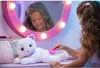 A young girl is brushing a white plush cat in front of a vanity mirror with lights. Anteprima dell’immagine prodotto