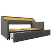 A gray upholstered daybed with its pull-out bed extended, revealing wooden slats and storage drawers underneath. The headboard features integrated LED lighting. Náhled obrázku produktu