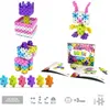 A collection of colorful building blocks arranged into various shapes, including a flower, a bunny, and a dog-like figure, along with a box and instruction booklet. Podgląd zdjęcia produktu