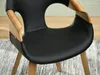 Close-up of a modern chair with black upholstery and wooden accents. Voir les images du produit