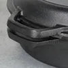 A close-up shot of the handle and rim of a black cast iron pot. Náhled obrázku produktu