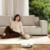 A woman and her cat relax on the floor next to a sofa, while a robot vacuum cleaner operates nearby. Anteprima dell’immagine prodotto