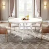 A white round dining table with chairs in a well-lit dining room. Náhled obrázku produktu