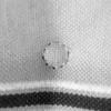 A close-up of a fabric with a small circular stitch repair. Produktbild-Vorschau