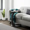 A side table with a book and cup sits next to a sofa, with a plant in the background. Produktbild-Vorschau