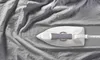 A close-up, top-down view of a white and gray steam iron on a wrinkled gray fabric. Náhled obrázku produktu