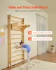 A young girl is stretching on a wooden wall bar in a room with a rug and curtains. Produktbild-Vorschau
