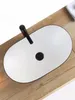 A white oval sink with a black faucet sits on a wooden countertop. Anteprima dell’immagine prodotto
