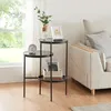 A three-tiered black metal side table with glass tops, placed next to a sofa in a living room. Anteprima dell’immagine prodotto