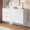 A white sideboard with gold accents and fluted detailing, placed in a room setting with a lamp and artwork. Podgląd zdjęcia produktu