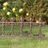A decorative metal fence in a garden setting with yellow flowers in the background. Produktbild-Vorschau