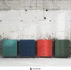 Four colorful metal dressers are lined up against a textured concrete wall. Anteprima dell’immagine prodotto
