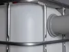 A close-up view of a white plastic tank with a metal cage and a gray pipe fitting attached. Náhled obrázku produktu