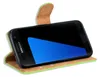 A black Samsung Galaxy S7 phone in a green and brown flip case, shown at an angle against a white background. Produktbild-Vorschau