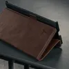 A close-up shot of a dark brown leather case for a tablet or e-reader, propped up on a dark surface. Anteprima dell’immagine prodotto