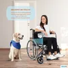 A woman sits in a wheelchair next to a golden retriever dog, with a door in the background. Produktbild-Vorschau