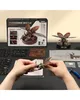 Hands assembling a mechanical rhinoceros beetle model kit, with the product box and other components laid out on a dark surface. Náhľad obrázku produktu